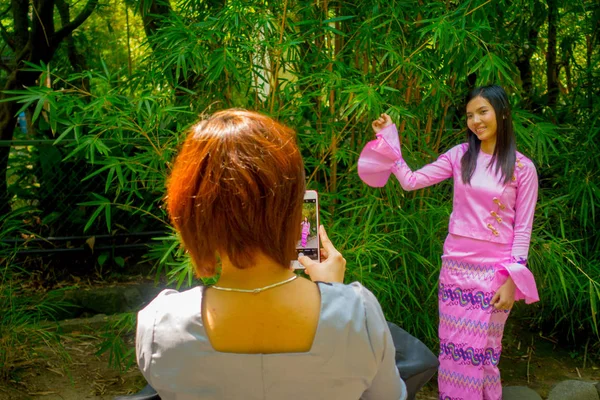 TOKYO, JAPÃO JUNHO 28 - 2017: Mulher não identificada tirando fotos para uma amiga que está posando para câmera usando um vestido rosa em Kamakura, Japão — Fotografia de Stock