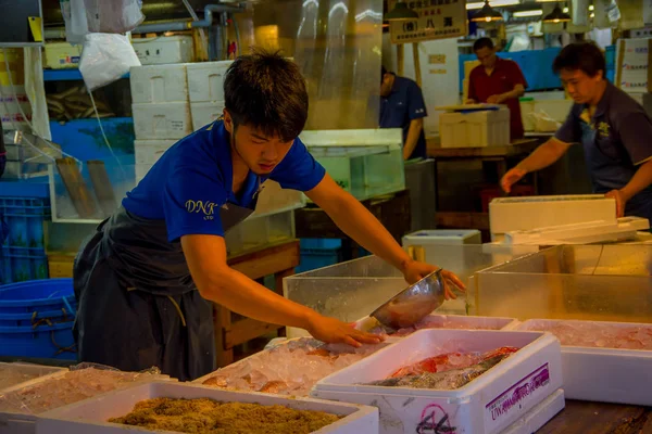 Tokyo, Japonya Haziran 28-2017: buz Tsukiji Balık pazarı, metalik bir pot ile toptan Tokyo Japonya, Tsukiji piyasa manipüle mavi elbise ve delantal, kimliği belirsiz biri en büyük