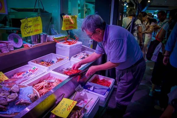 TOKYO, JAPON 28 JUIN 2017 : Homme non identifié utilisant ses mains pour tenir un plateau en plastique blanc avec des crevettes rouges au marché aux poissons de Tsukiji en gros à Tokyo au Japon, le marché de Tsukiji est le plus gros — Photo
