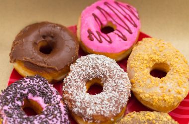 Ahşap arka plan kırmızı bir plaka üzerinde farklı lezzetli çeşitli çörekler sırlı