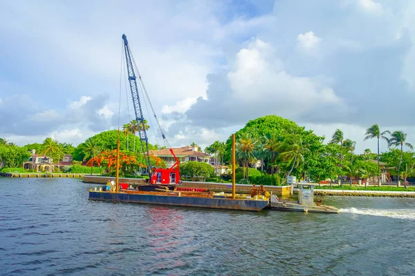 FORT LAUDERDALE, États-Unis - 11 JUILLET 2017 : Structure flottante avec une machine rouge sur elle naviguant sur la promenade fluviale, avec quelques bâtiments en copropriété derrière à Fort Lauderdale, Floride — Photo