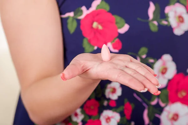 Acercamiento de una mano de mujer, sosteniendo en su mano abierta una tableta o supositorio vaginal de gelatina blanda, tratamiento de enfermedades de los órganos reproductivos de las mujeres y prevención de la salud de las mujeres —  Fotos de Stock