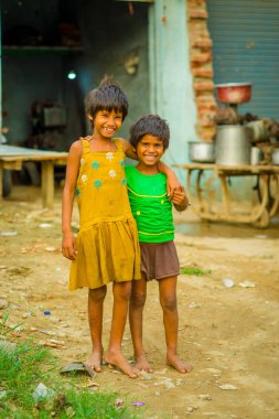 Jaipur, Hindistan - 20 Eylül 2017: Sarılma ve gülümseyen, sokakta sarhoş bir zemin üzerinde sarı bir kirli bluz ve yeşil tişört ve kahverengi pantolon giyen iki güzel kız portresi