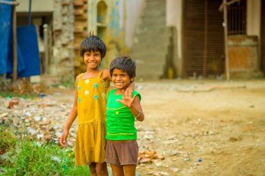 Jaipur, Hindistan - 20 Eylül 2017: Sarılma ve gülümseyen, sokakta sarhoş bir zemin üzerinde sarı bir kirli bluz ve yeşil tişört ve kahverengi pantolon giyen iki güzel kız portresi