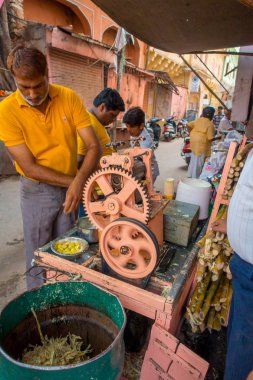 Jaipur, Hindistan - 20 Eylül 2017: şeker kamışı, Jaipur bir sokakta ferahlatıcı suyu ayıklamak için bir makine ile çalışan kimliği belirsiz erkeğin
