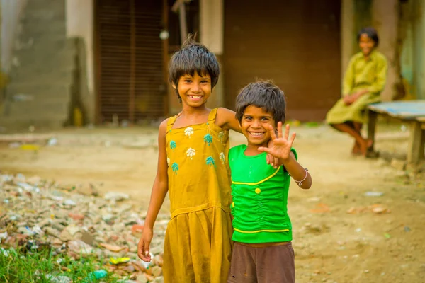 Jaipur, Hindistan - 20 Eylül 2017: Sarılma ve gülümseyen, sokakta sarhoş bir zemin üzerinde sarı bir kirli bluz ve yeşil tişört ve kahverengi pantolon giyen iki güzel kız portresi