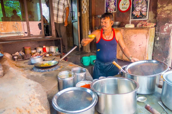 Jaipur, indien - 20. september 2017: unbekannter mann kocht indisches essen in einem metallischen tablett über glühenden felsen in küche, umgeben von riesigen kochtöpfen, in jaipur, indien — Stockfoto