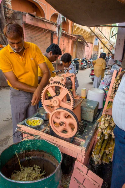 Jaipur, Hindistan - 20 Eylül 2017: şeker kamışı, Jaipur bir sokakta ferahlatıcı suyu ayıklamak için bir makine ile çalışan kimliği belirsiz erkeğin