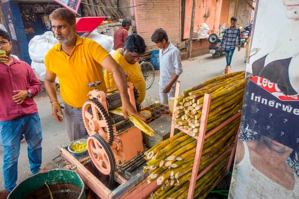 Jaipur, Hindistan - 20 Eylül 2017: şeker kamışı, Jaipur bir sokakta ferahlatıcı suyu ayıklamak için bir makine ile çalışan kimliği belirsiz erkeğin