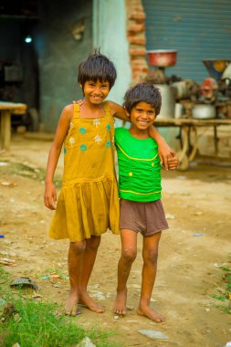 Jaipur, Hindistan - 20 Eylül 2017: Sarılma ve gülümseyen, sokakta sarhoş bir zemin üzerinde sarı bir kirli bluz ve yeşil tişört ve kahverengi pantolon giyen iki güzel kız portresi