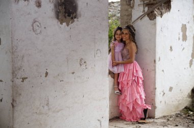 Genç kadın ve gülümseyerek, eski bir bina içinde poz pembe Prenses elbise giyen sevimli küçük kızı