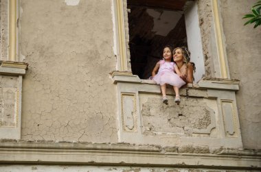 Güzel kadın ve gülümseyen sevimli küçük kızı, küçük bir kız iken bir pencere kalede poz bir pembe Prenses elbise giyen pencerede oturuyor