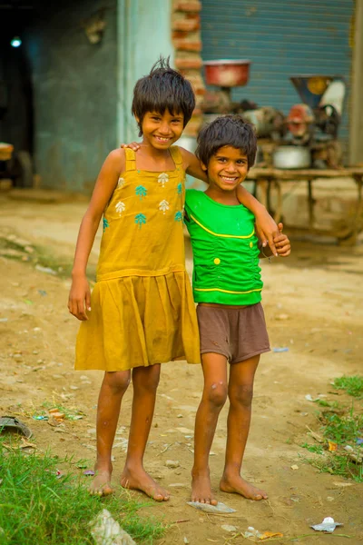 Jaipur, Hindistan - 20 Eylül 2017: Sarılma ve gülümseyen, sokakta sarhoş bir zemin üzerinde sarı bir kirli bluz ve yeşil tişört ve kahverengi pantolon giyen iki güzel kız portresi