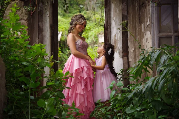Güzel kadın ve birbirimizi ve gülümseyerek, bir pembe Prenses elbise giyen sevimli küçük kızı
