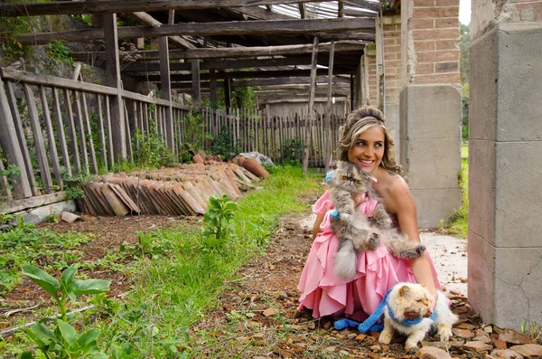 Bella donna sorridente che indossa un vestito rosa di principessa che abbraccia il suo gatto all'aperto — Foto Stock