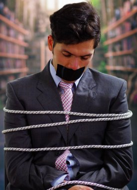 Arka plan bulanık içinde onun ağız içinde siyah bant ile işadamı ip, sandalyeyle tuzak