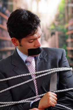 İşadamı ip, sandalyeyle ağzında, siyah bir bant ile ipi arka plan bulanık bir bıçak ile kesmek tuzak