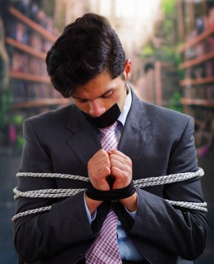 Siyah bir bant içinde onun ağız ve arka plan bulanık elinde ile işadamı ip, sandalyeyle tuzak