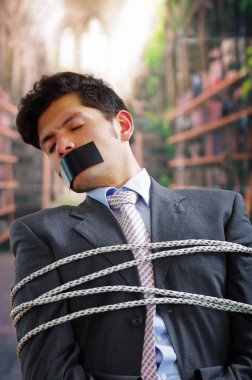 Siyah bir bant içinde onun ağız ve arka plan bulanık elinde ile işadamı ip, sandalyeyle tuzak