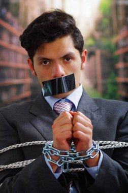 İp, sandalyeyle siyah bir bant içinde onun ağız ve arka plan bulanık elinde bir zincir ile sıkışmış bir işadamı yakın çekim