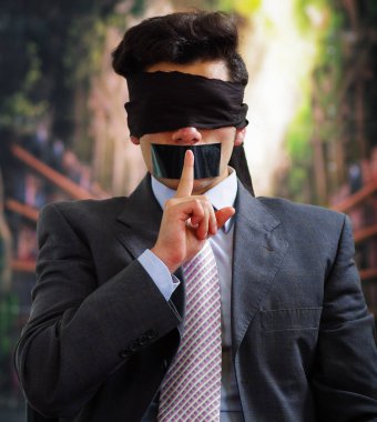 İşadamı, ağzına ağzına arka plan bulanık içinde bir parmak bir sessizlik işaretiyle yapıyor siyah bir bant ile