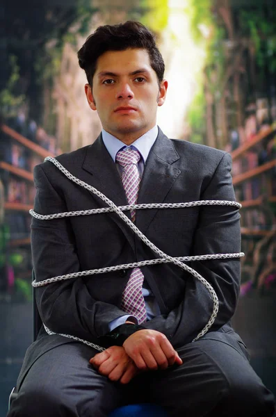 Uomo d'affari intrappolato in una sedia con corda su sfondo sfocato — Foto Stock