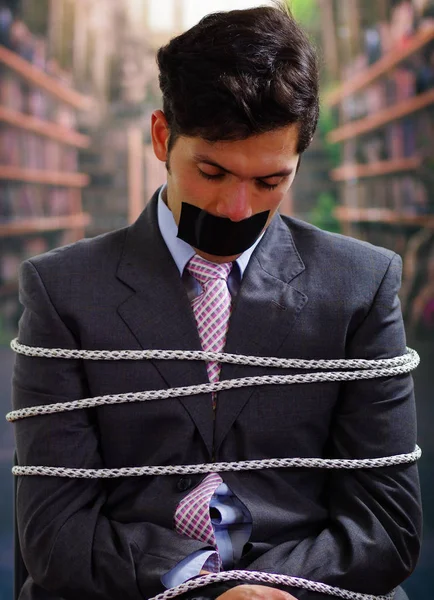 Arka plan bulanık içinde onun ağız içinde siyah bant ile işadamı ip, sandalyeyle tuzak