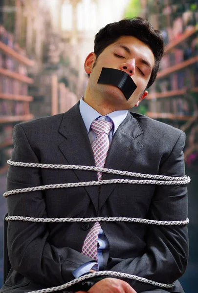 Arka plan bulanık içinde onun ağız içinde siyah bant ile işadamı ip, sandalyeyle tuzak