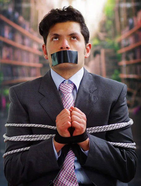 Siyah bir bant içinde onun ağız ve arka plan bulanık elinde ile işadamı ip, sandalyeyle tuzak