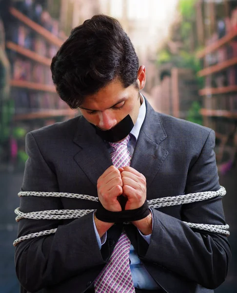 Siyah bir bant içinde onun ağız ve arka plan bulanık elinde ile işadamı ip, sandalyeyle tuzak