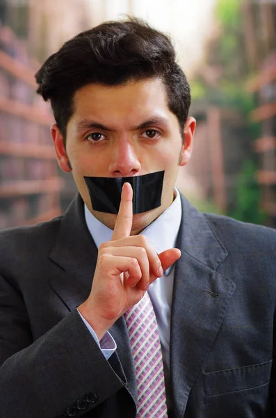 背景をぼかして、彼の口から指を沈黙サインをして口の中に黒いテープを持ったビジネスマン — ストック写真