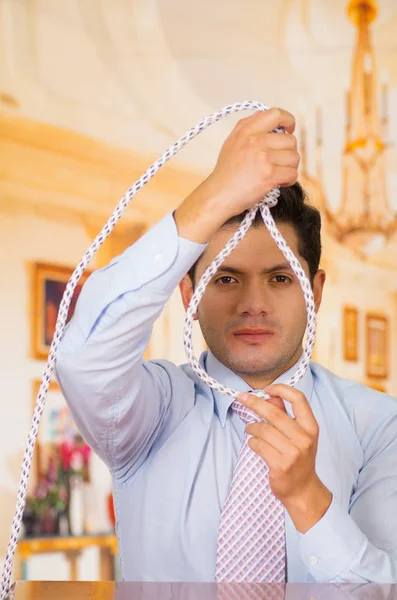 Депрессивный человек с веревкой в руках, готовящийся надеть на шею, на заднем плане комнаты — стоковое фото