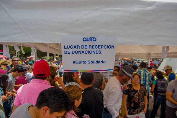 Quito, Équateur - 17 avril 2016 : Citoyens non identifiés de Quito fournissant de la nourriture, des vêtements, des médicaments et de l'eau de secours en cas de catastrophe, avec un signe informatif de lieu d'accueil — Photo