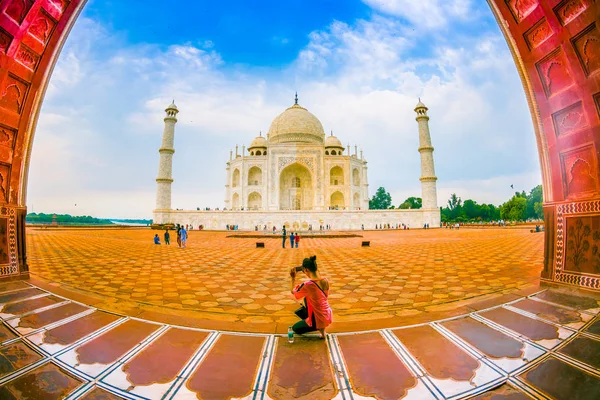 Agra, India - 20 de septiembre de 2017: Mujer no identificada sentada en el suelo y enjooying la hermosa vista del Taj Mahal a través de una enorme puerta, es un mausoleo de mármol blanco marfil en la orilla sur de — Foto de Stock