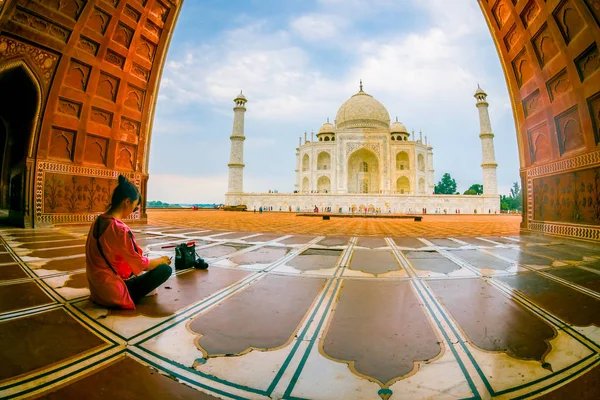 アグラ、インド - 2017 年 9 月 20 日: 巨大なドアを通って、タージ ・ マハルの美しい景色を楽しんで、床に座っている正体不明の女性はの南銀行にアイボリー ホワイト大理石の霊廟 — ストック写真