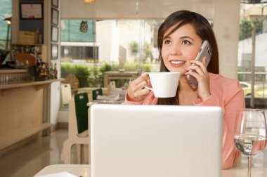 Çalışma ve o cep telefonunu arama yapmak için kullanırken kahve içme bir genç güzel iş kadını yakın çekim. İş kavramı