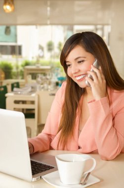 Pembe bir ceket ve arama yapmak için cep telefonunu kullanarak bir genç güzel gülümseyen iş kadını yakın çekim. İş kavramı