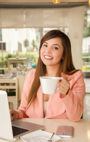 Primo piano di una giovane bella donna d'affari sorridente che lavora e tiene con una mano una tazza di caffè. Concetto aziendale — Foto Stock