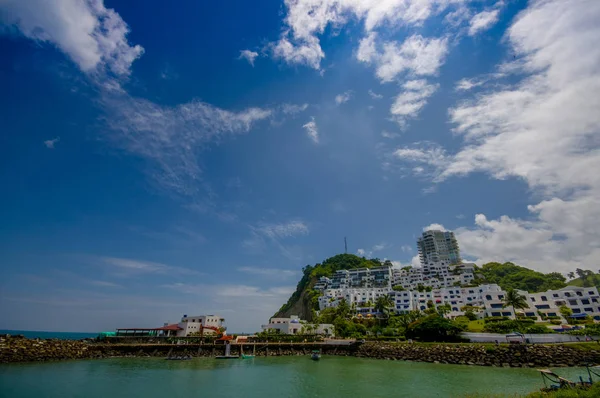 Prachtige rotsachtige strand met een structuur van de gebouwen van hotels achter in een mooie dag met mooi weer in een blauwe hemel in hetzelfde, Ecuador — Stockfoto