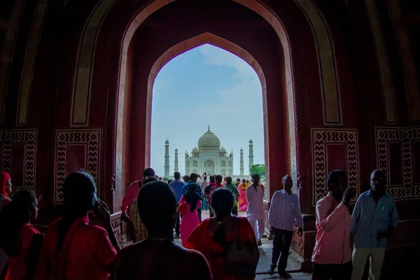 Agra, India - 20 settembre 2017: La folla di persone che cammina attraverso una grande porta con il Taj Mahal all'orizzonte, è un mausoleo di marmo bianco avorio sulla riva sud del fiume Yamuna nella — Foto Stock