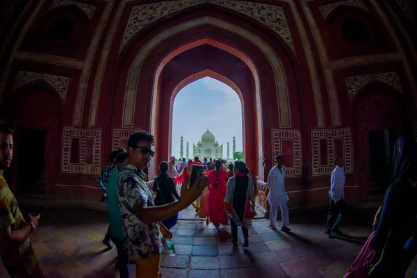 Agra, India - 20 settembre 2017: La folla di persone che cammina attraverso una grande porta con il Taj Mahal all'orizzonte, è un mausoleo di marmo bianco avorio sulla riva sud del fiume Yamuna nella — Foto Stock