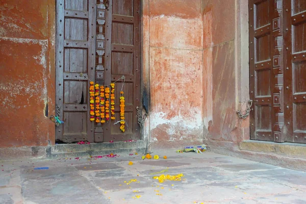 Vista esterna di una porta in legno con alcuni fiori gialli appesi, in una vecchia casa, nella città di Agra vicino a Taj Mahal in India — Foto Stock
