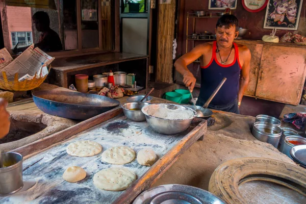 Jaipur, India - 20 September 2017: Onbekende man Indiaas eten koken boven een houten tafel met wat materiaal ernaast, in keuken in Jaipur, India — Stockfoto