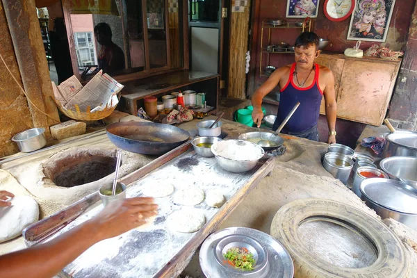 Jaipur, India - 20 September 2017: Onbekende man Indiaas eten koken boven een houten tafel met wat materiaal ernaast, in keuken in Jaipur, India — Stockfoto