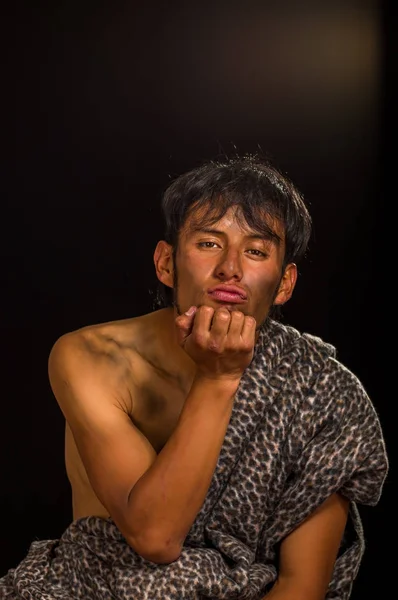 Close up of funny prehistoric man with his hand under his chin, giving a kiss, in a black background — Stockfoto