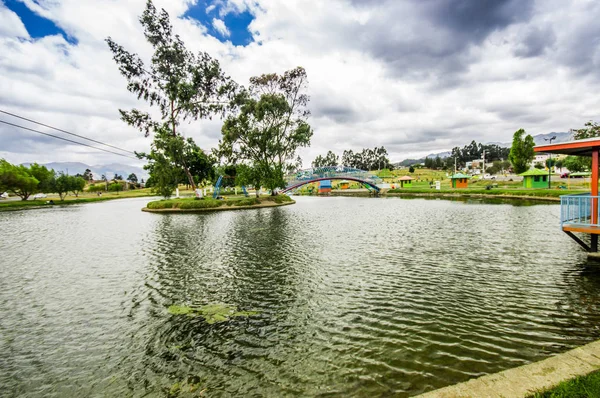 Bella giornata di un lago artificiale situato nel mezzo di un parco, con il riflesso in acqua, nella città di Cayambe, Ecuador — Foto Stock