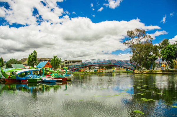 Beautiful day of an artificial lake located in the midle of a park, with some boats of animals in the water with the reflection in the city of Cayambe, Ecuador