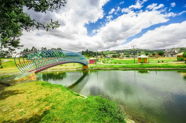 Красивый красочный мост через искусственное озеро, расположенное в центре парка с отражением в воде, в городе Каямбе, Эквадор — стоковое фото