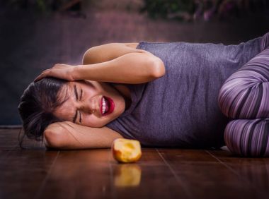 Anorexy acı, çığlık ve onun baş acı acı elma önünde, kollarını ile ahşap zemin üzerinde bulanık bir arka planda döşeme güzel kız