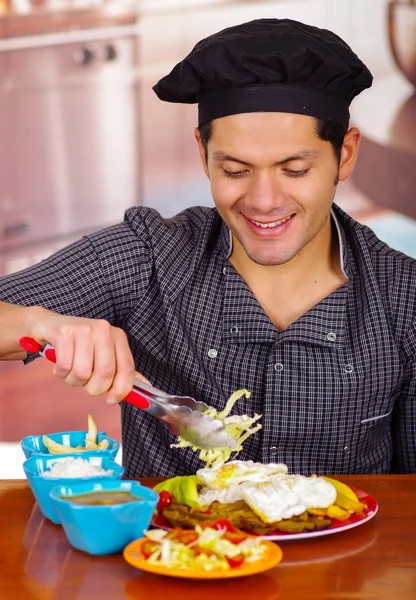 Улыбающийся красивый мужчина в черной шляпе, поедающий чураско, эквадорскую кухню — стоковое фото